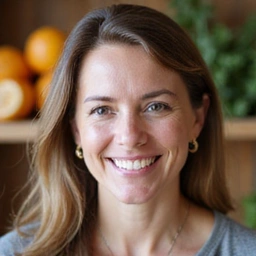 Profesjonalny portret nutricjologa, uśmiechnięta kobieta w średnim wieku, w tle rozmyte elementy związane ze zdrowym odżywianiem.